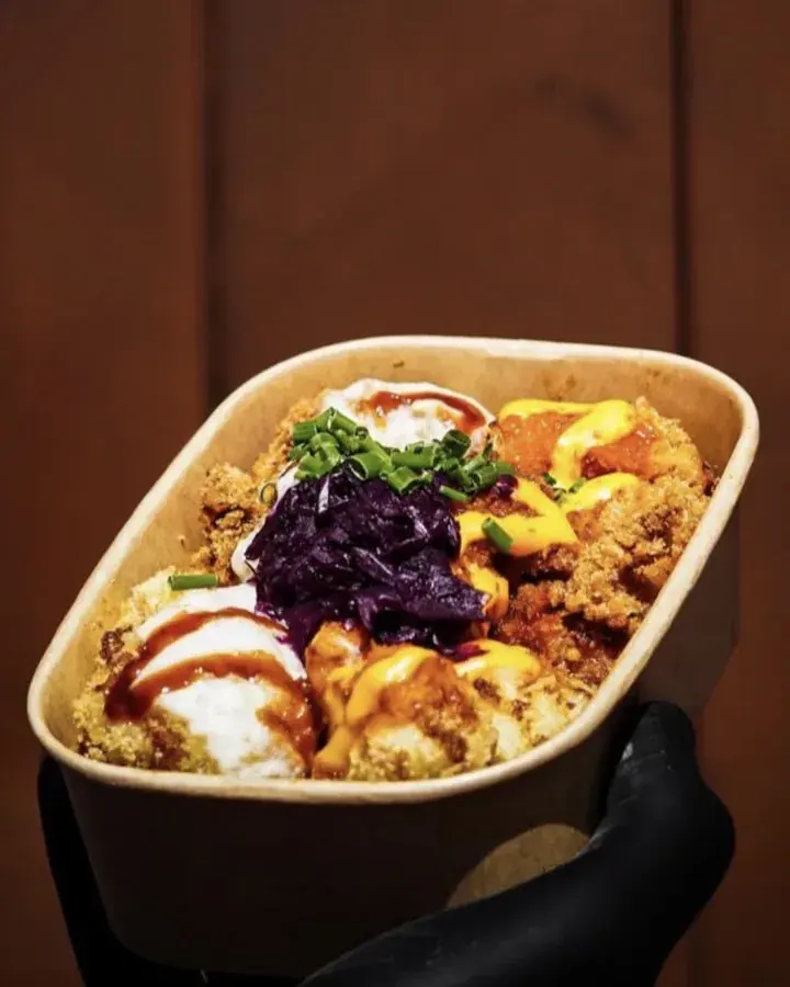 Chicken Parmo Teller in der Kraftpapier-Schale: frittierte Chicken Tenders und Blumenkohl-Wings mit Soßen, Rotkohl und Schnittlauch