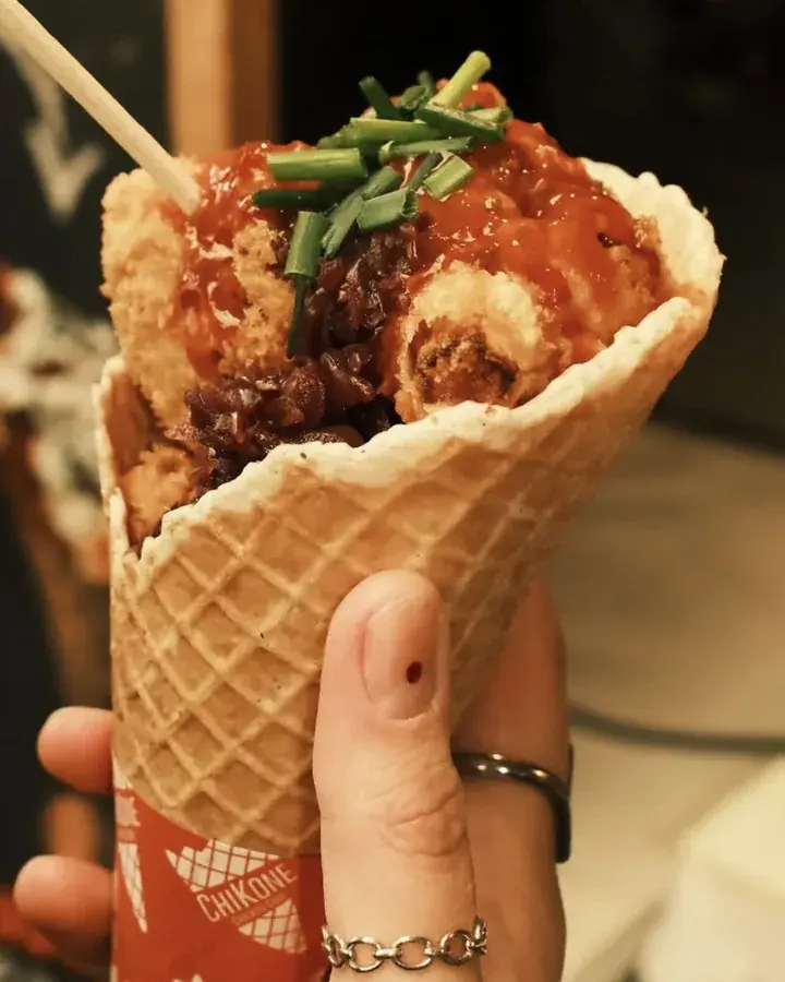 Veggie Cone in der Hand: frittierte Blumenkohl-Wings mit Soße und Schnittlauch im Waffelcone mit Chikone-Banderole